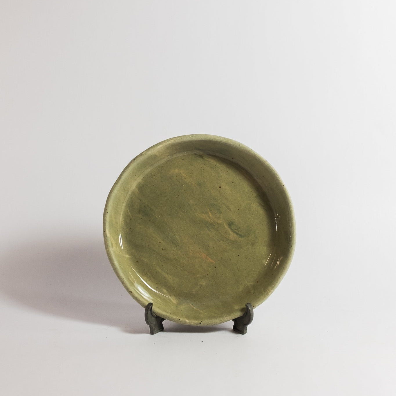 Green ceramic plate on a stand against a white background