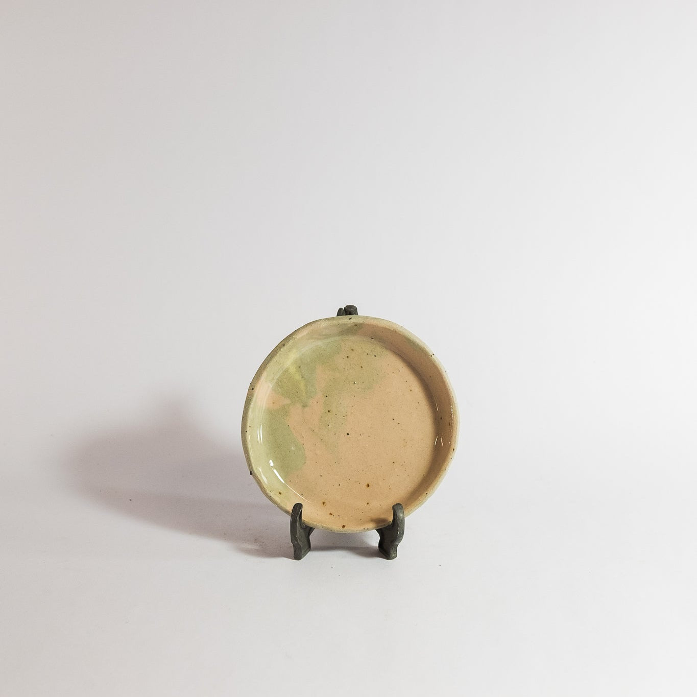 Small ceramic plate on a stand against a plain background