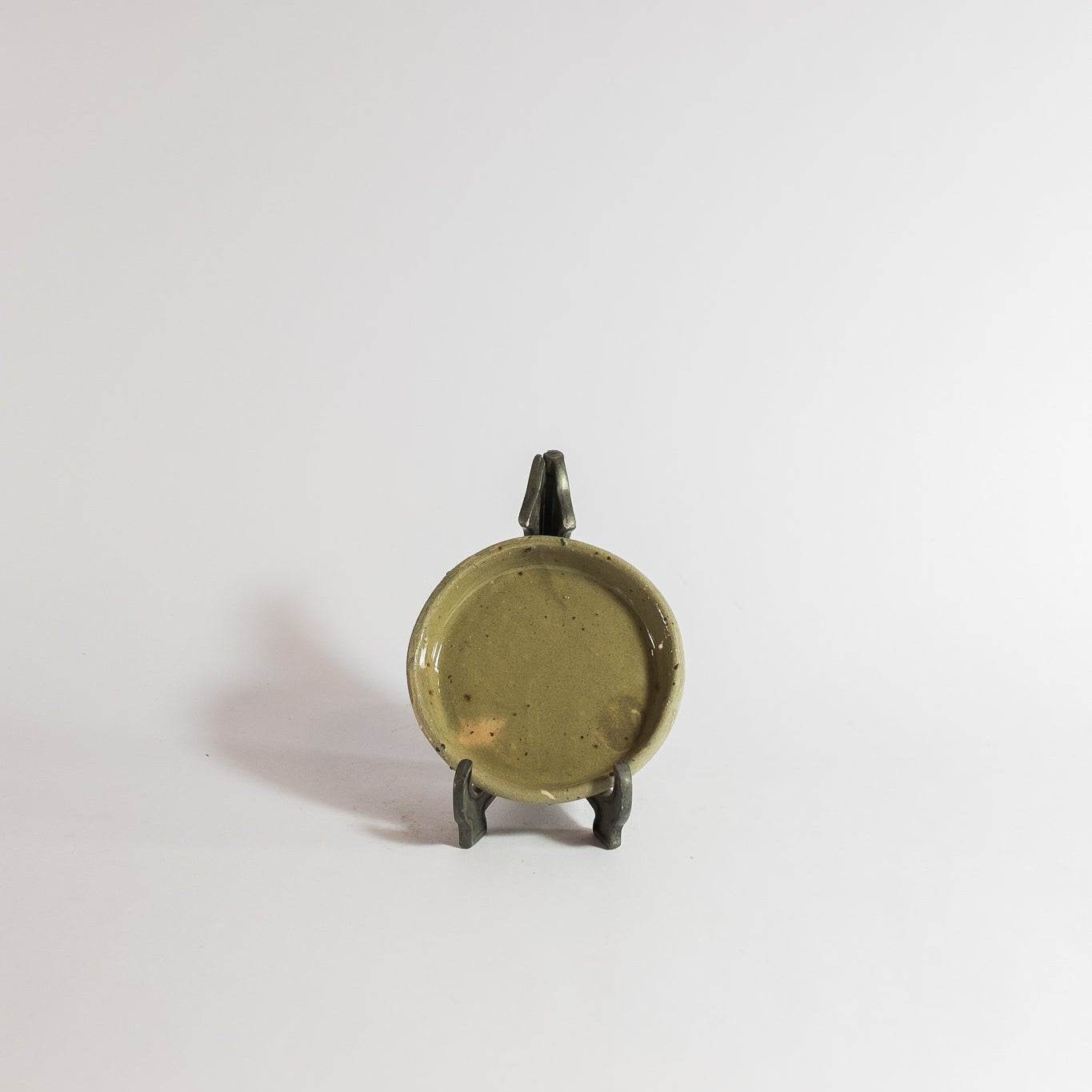 Small bronze object on a stand against a white background