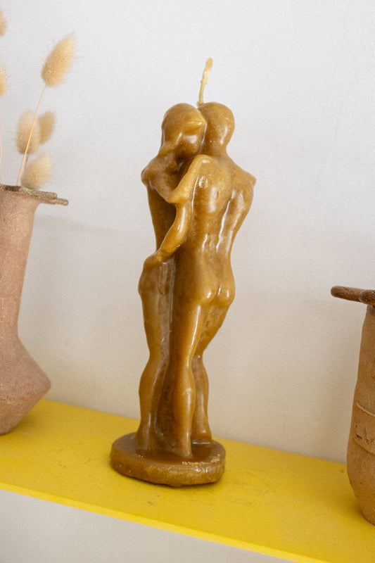 Honey scent candle shaped like a couple embracing on a yellow surface with a white background