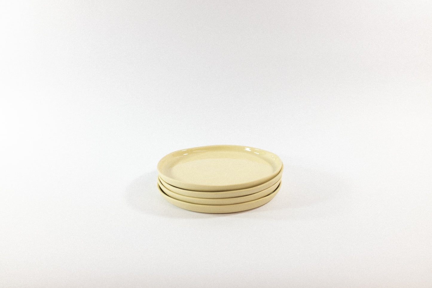 Handmade cream desser plates stacked on a white background