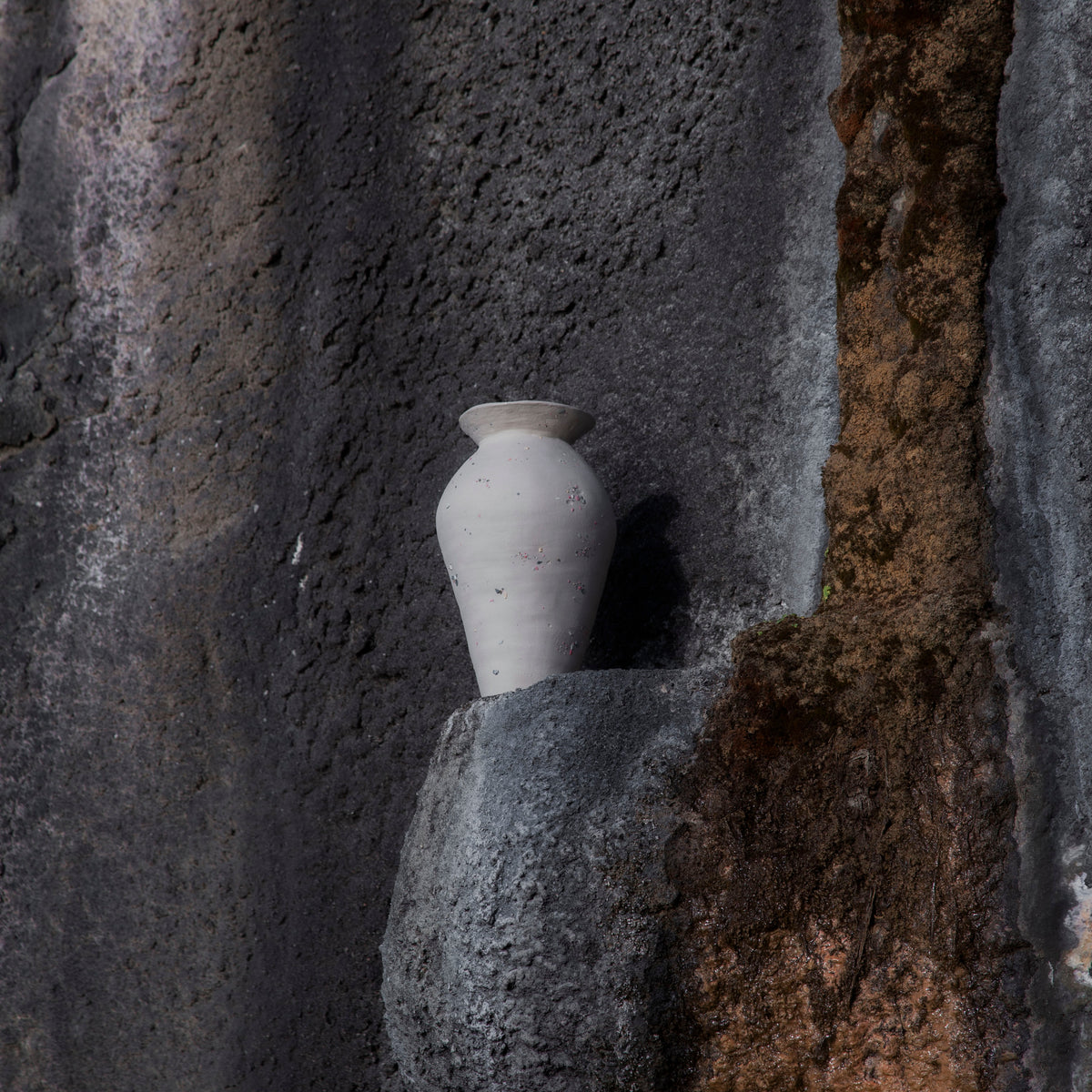 Handmade big funfetti stoneware vase on the textured stone wall