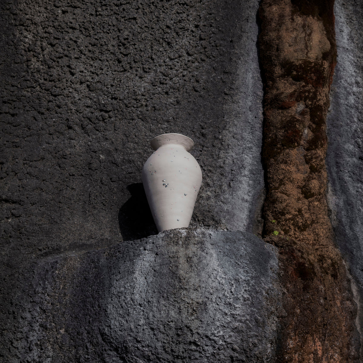 Handmade stoneware funfetti vase on a textured stone surface with a tree trunk in the background