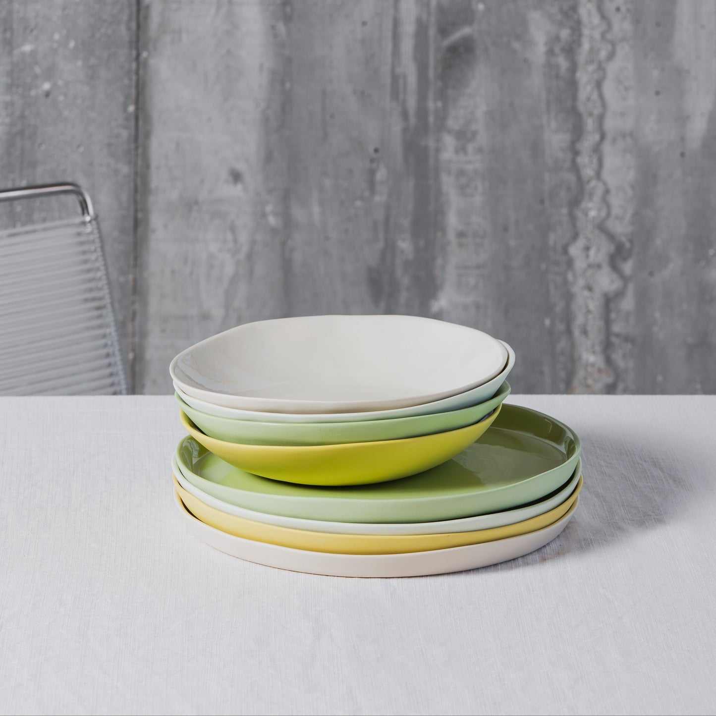 Stack of colorful porcelain plates on a white table with a gray textured background