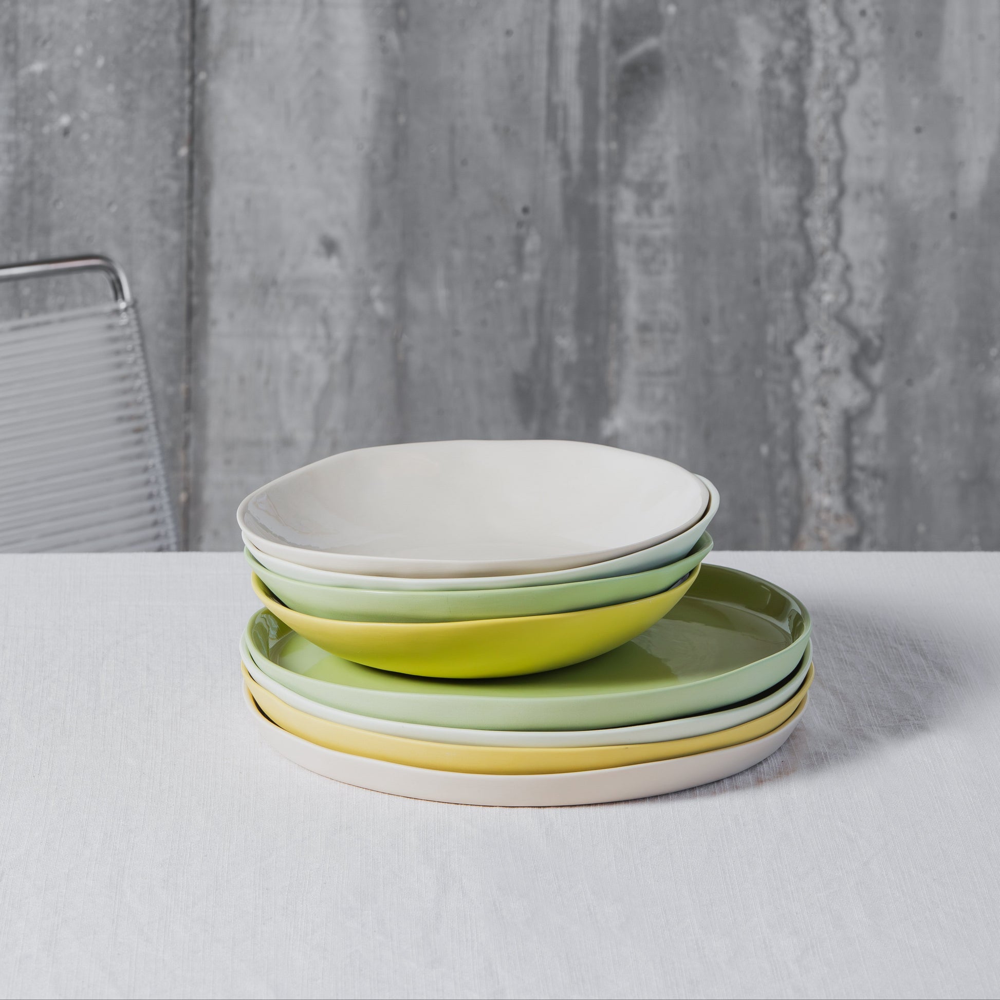 Stack of colorful porcelain plates on a white table with a gray textured background