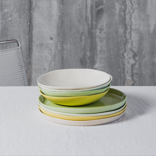 Stack of colorful porcelain plates on a white table with a gray textured background