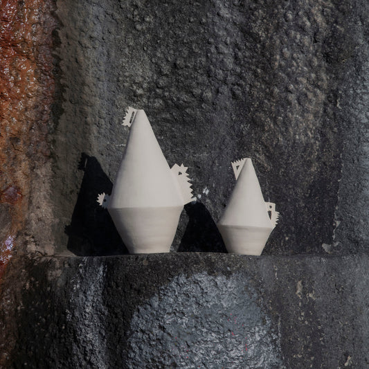 White cone shaped (soliflor) vase with details on a textured stone surface