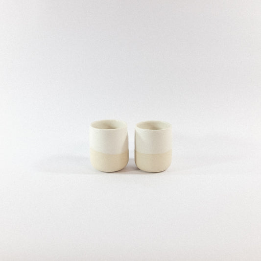 Two white stoneware tumbler ceramic cups on a white  background
