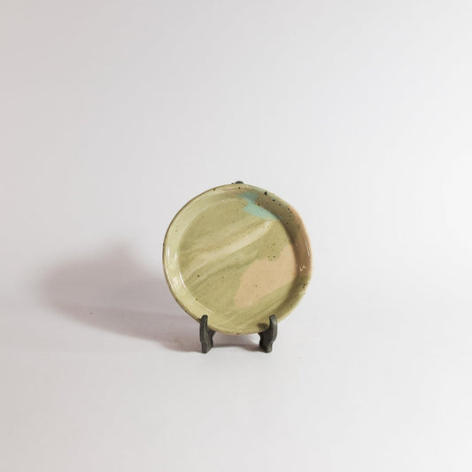 Small ceramic plate on a stand against a plain background