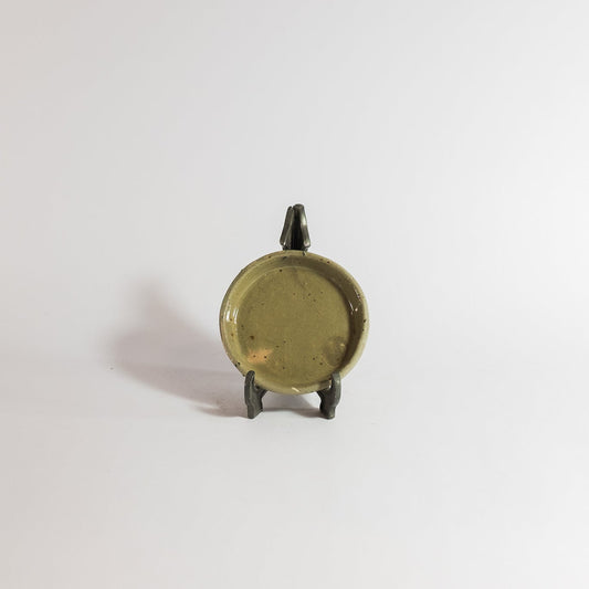 Small bronze object on a stand against a white background