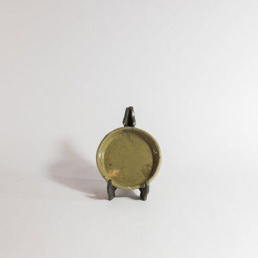 Small bronze object on a stand against a white background